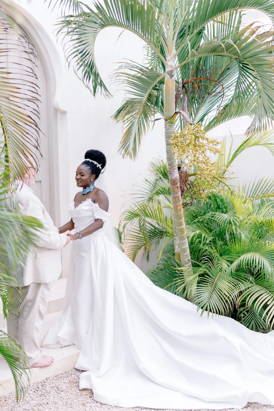 Betty in a white gown among palms and white arches
