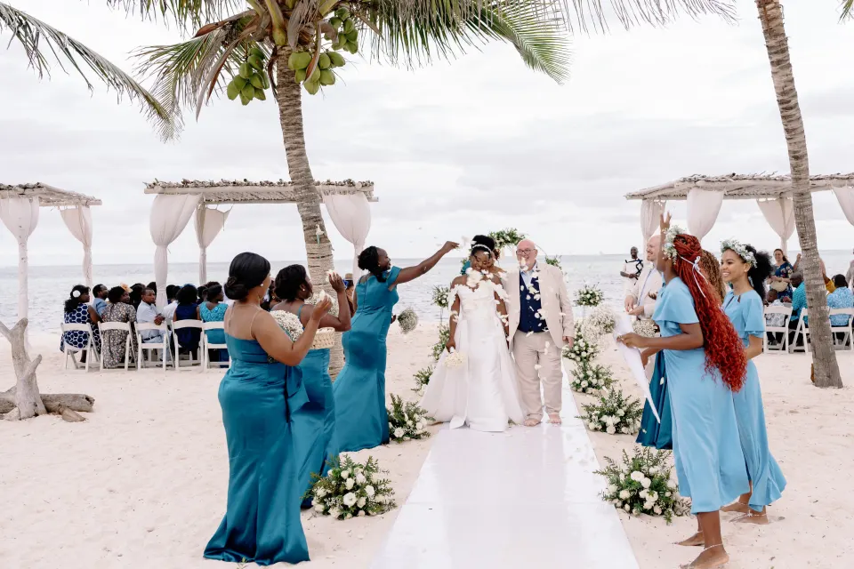 A beach wedding aisle lined with friends in teal