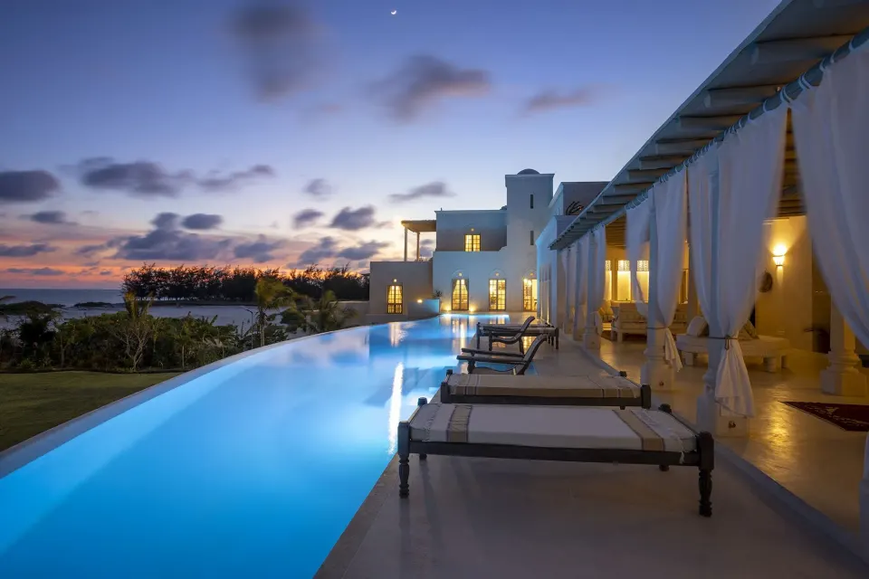 The 40-metre infinity pool at dusk, lanterns lit along the terrace