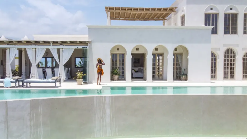 The villa's white arches and pool in daylight